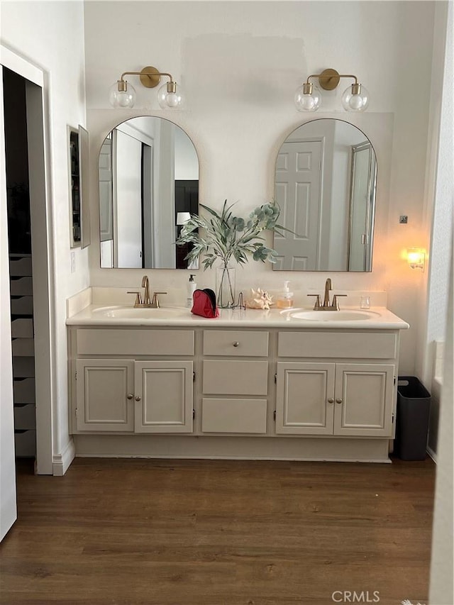 full bath with double vanity, a sink, and wood finished floors