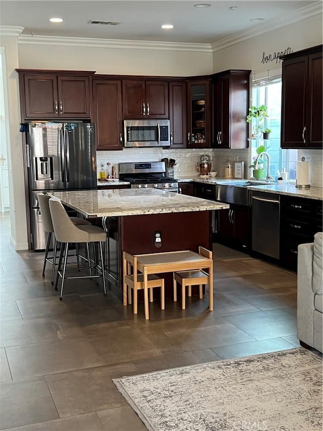 kitchen featuring a sink, light stone countertops, tasteful backsplash, stainless steel appliances, and dark brown cabinets