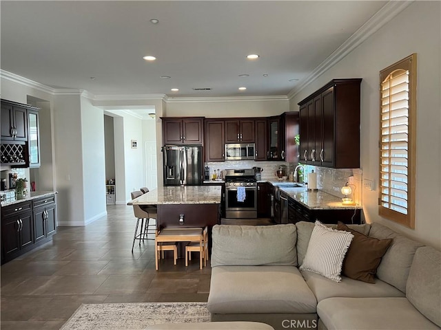 kitchen featuring open floor plan, a kitchen breakfast bar, a sink, and stainless steel appliances