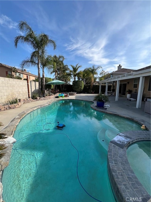 view of swimming pool with fence, a pool with connected hot tub, and a patio area
