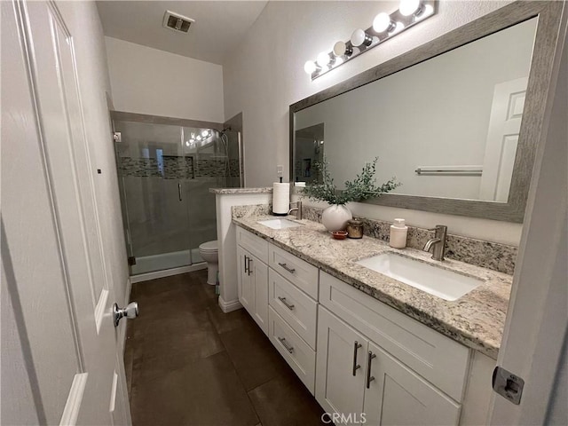 bathroom with a stall shower, double vanity, toilet, and a sink