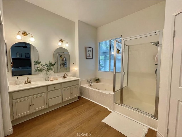 bathroom featuring wood finished floors, a sink, a jetted tub, and a shower stall