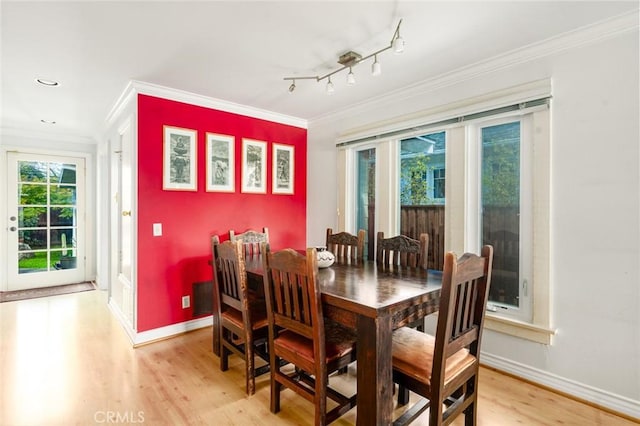 dining space with ornamental molding, baseboards, and light wood finished floors