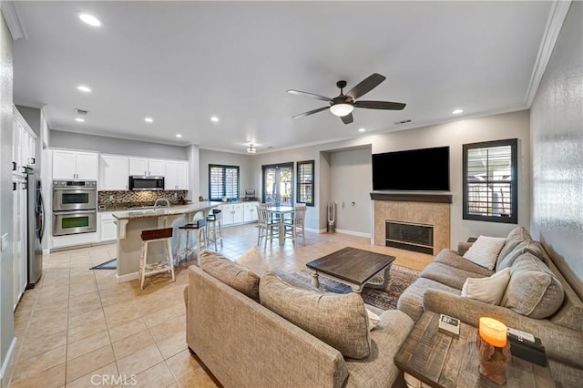 living room with ceiling fan, light tile patterned flooring, recessed lighting, ornamental molding, and a tiled fireplace