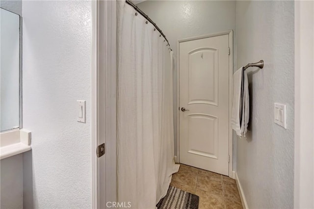 bathroom featuring tile patterned floors, baseboards, and a textured wall