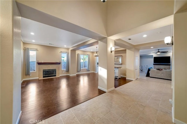 unfurnished living room with recessed lighting, wood finished floors, a glass covered fireplace, baseboards, and a ceiling fan