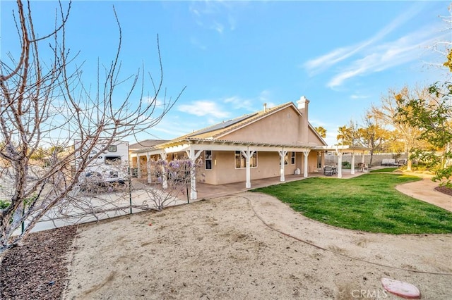 back of house with a patio, stucco siding, a pergola, and a lawn