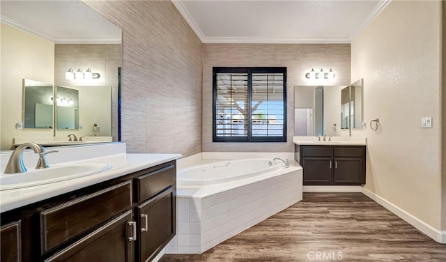 bathroom featuring a sink, crown molding, two vanities, a garden tub, and wood finished floors