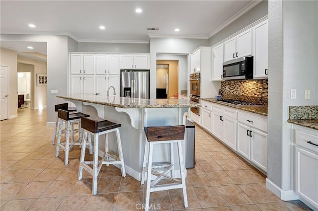 kitchen featuring a kitchen breakfast bar, light tile patterned floors, decorative backsplash, appliances with stainless steel finishes, and visible vents