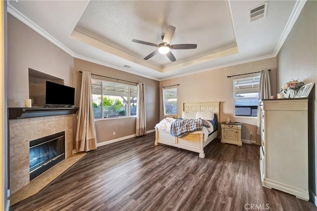 bedroom featuring visible vents, a raised ceiling, dark wood-style flooring, and crown molding
