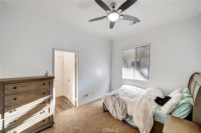 bedroom featuring crown molding, a ceiling fan, visible vents, baseboards, and carpet floors