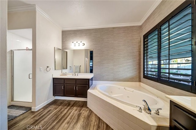 bathroom with a shower stall, vanity, ornamental molding, a tub with jets, and wood finished floors