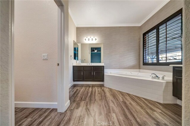 bathroom featuring wood finished floors, crown molding, a bath, and baseboards