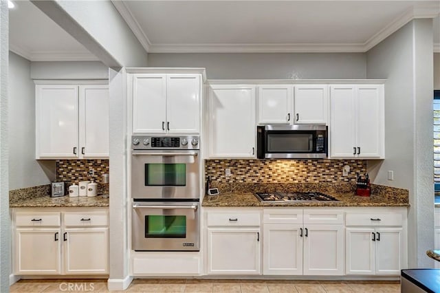 kitchen featuring dark stone countertops, white cabinets, appliances with stainless steel finishes, and tasteful backsplash
