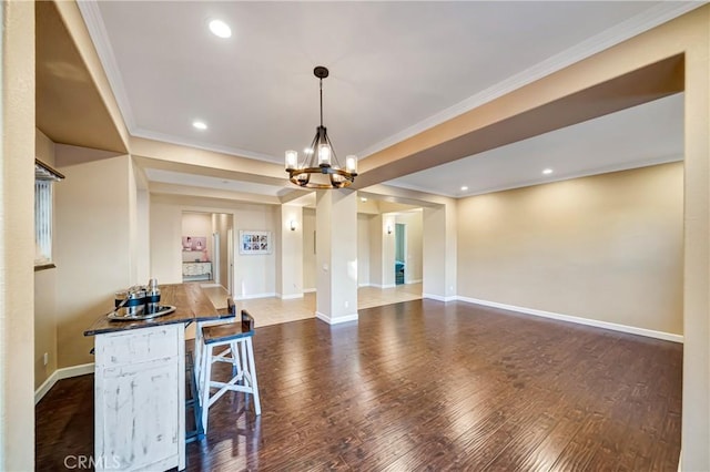 dining room featuring crown molding, a notable chandelier, dark wood-style flooring, and baseboards