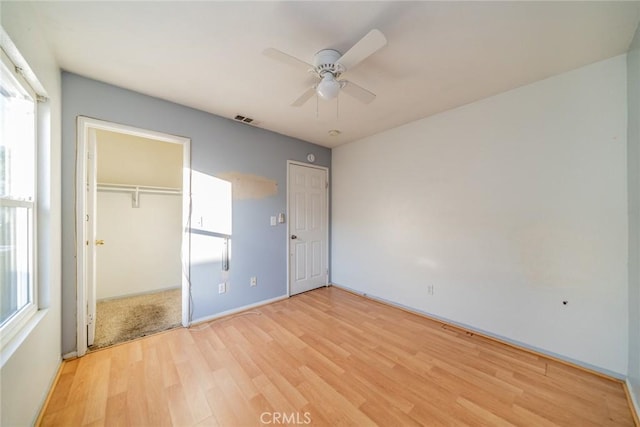 unfurnished bedroom with a closet, visible vents, light wood-type flooring, and multiple windows