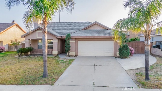 view of front of house featuring a tiled roof, stucco siding, a front lawn, a garage, and driveway