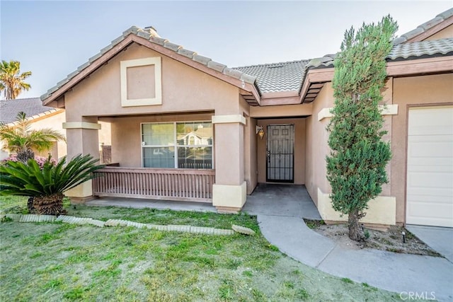 doorway to property featuring a tiled roof, covered porch, and stucco siding