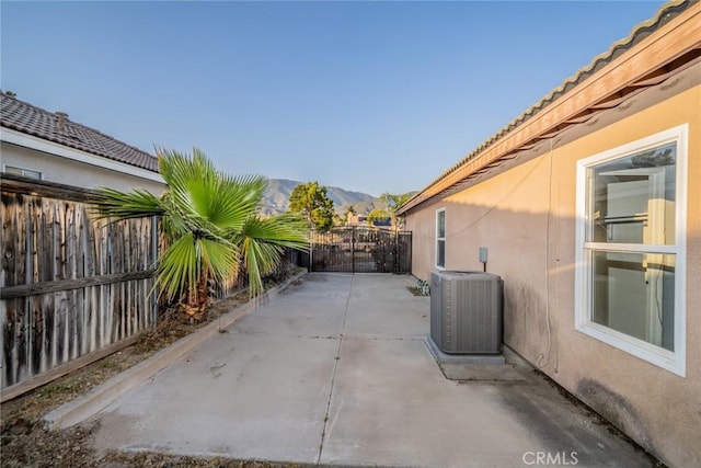 view of patio / terrace with a mountain view, fence, a gate, and central air condition unit