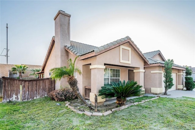 view of front of home with a front yard, a tiled roof, fence, and stucco siding