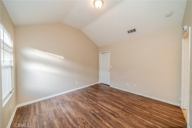 unfurnished bedroom featuring visible vents, baseboards, wood finished floors, and lofted ceiling