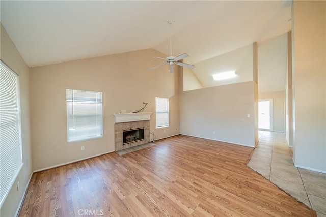 unfurnished living room featuring high vaulted ceiling, a ceiling fan, a fireplace, and light wood finished floors