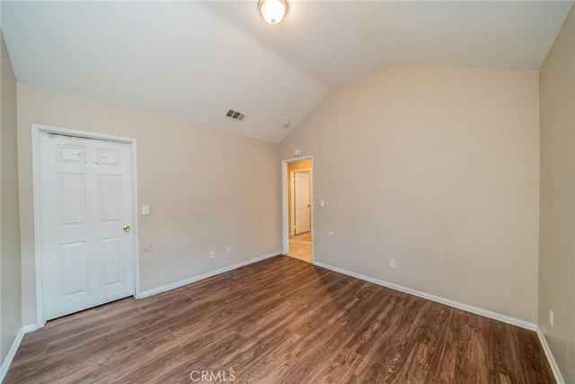 spare room with visible vents, baseboards, vaulted ceiling, and wood finished floors
