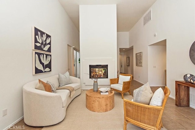 233 Lake Shore Dr, Rancho Mirage, CA 92270 - living area with a lit fireplace, a towering ceiling, baseboards, and tile patterned floors
