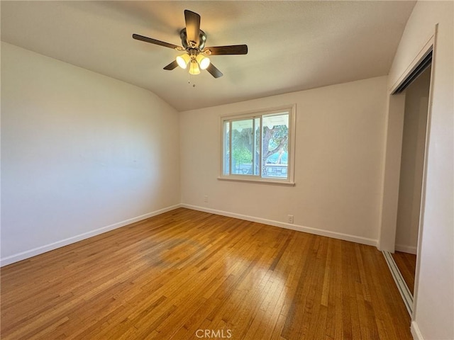 unfurnished bedroom with lofted ceiling, light wood-style floors, ceiling fan, a closet, and baseboards
