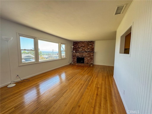 unfurnished living room featuring baseboards, visible vents, a fireplace, and light wood-style flooring