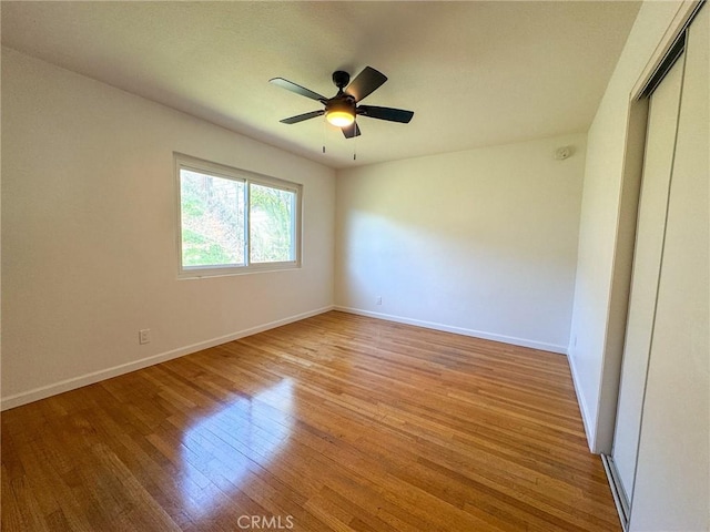unfurnished room with light wood-style floors, a ceiling fan, and baseboards