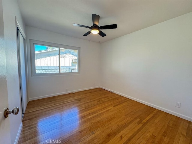 empty room with ceiling fan, light wood-type flooring, and baseboards