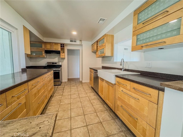 kitchen featuring glass insert cabinets, stainless steel appliances, under cabinet range hood, a sink, and visible vents