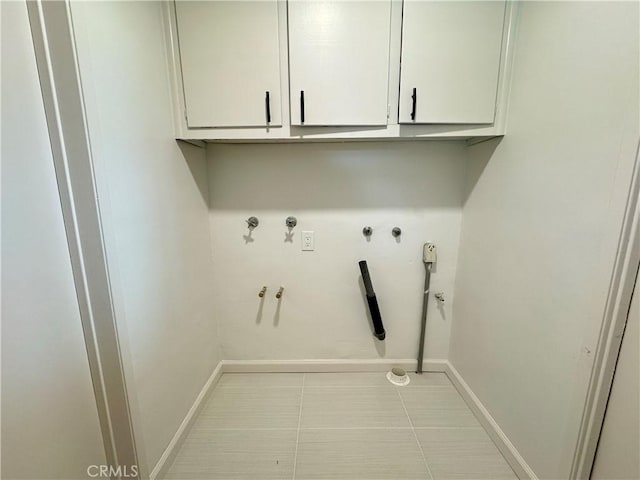 washroom featuring hookup for a gas dryer, tile patterned flooring, cabinet space, and baseboards