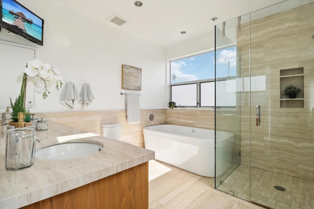 bathroom with vanity, a stall shower, a bath, and visible vents