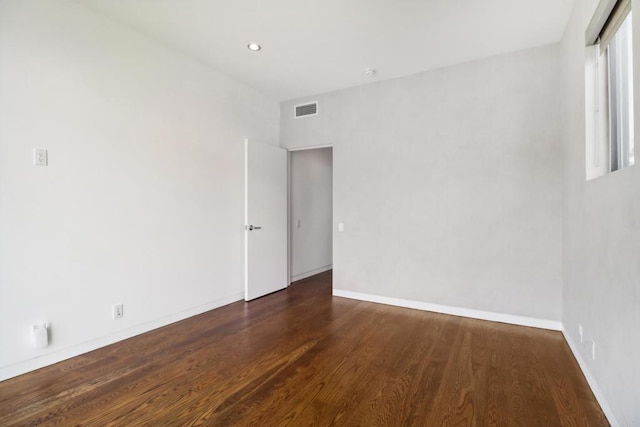 unfurnished room featuring baseboards, visible vents, and wood finished floors