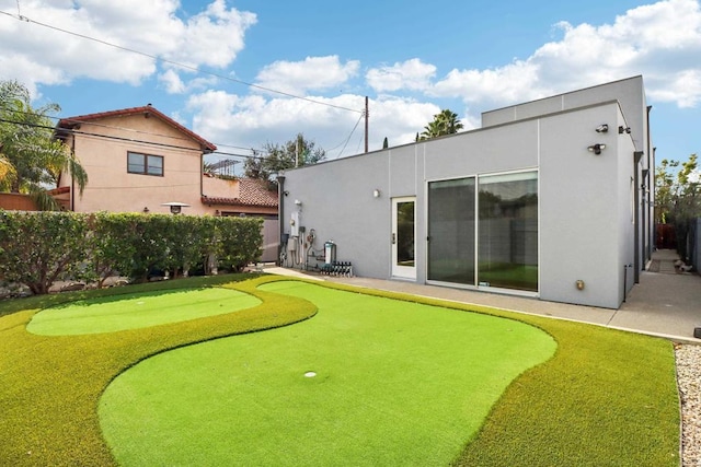 rear view of house featuring fence and stucco siding