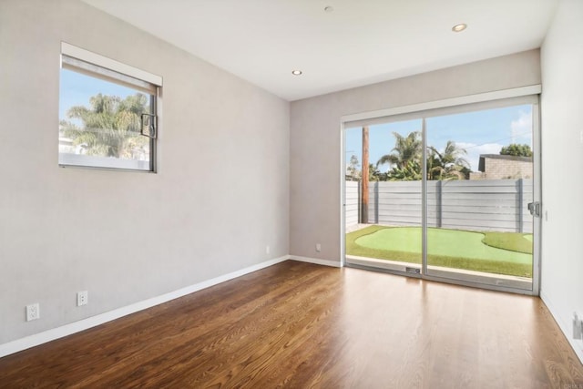 unfurnished room featuring baseboards, a wealth of natural light, and wood finished floors