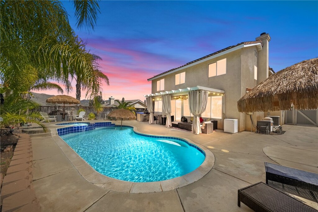 view of pool featuring a patio, fence, and a pool with connected hot tub