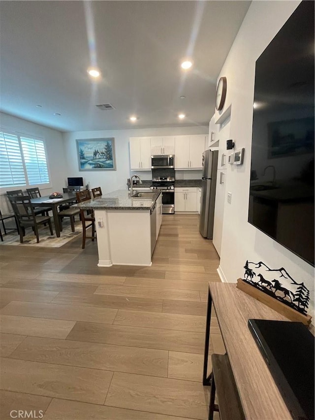 kitchen with stainless steel appliances, light wood-style flooring, white cabinets, recessed lighting, and a sink