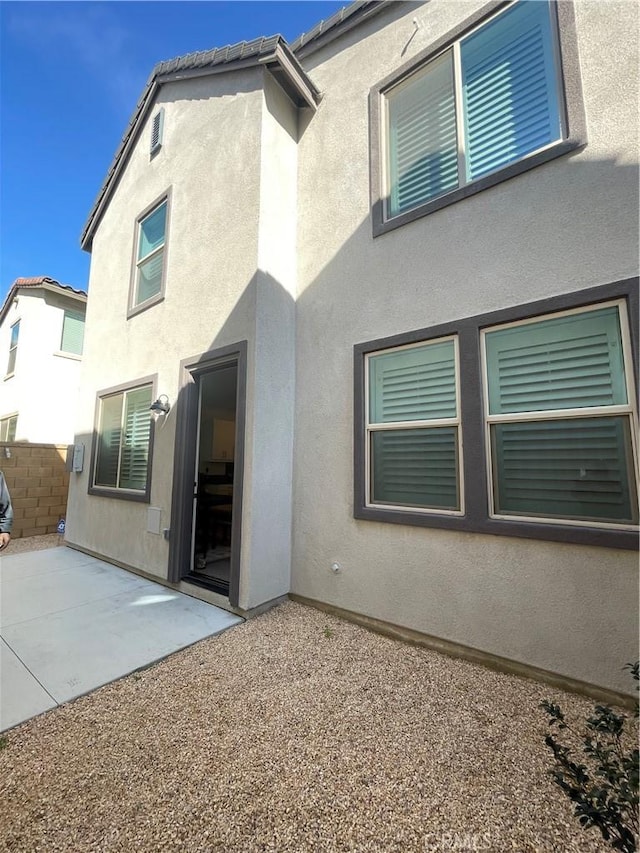 back of property with stucco siding and a patio