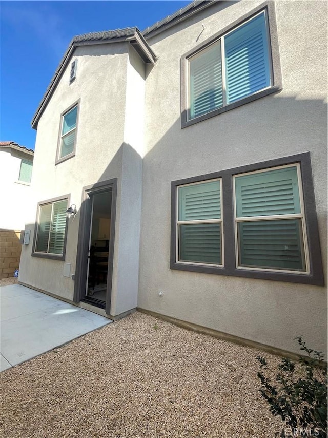 rear view of property featuring stucco siding and a patio area
