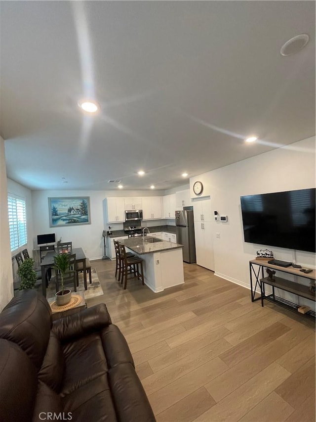living area with recessed lighting, light wood finished floors, and baseboards