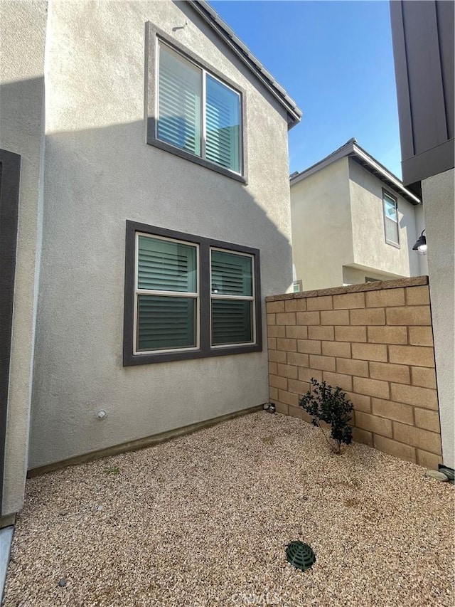 view of property exterior featuring stucco siding and fence