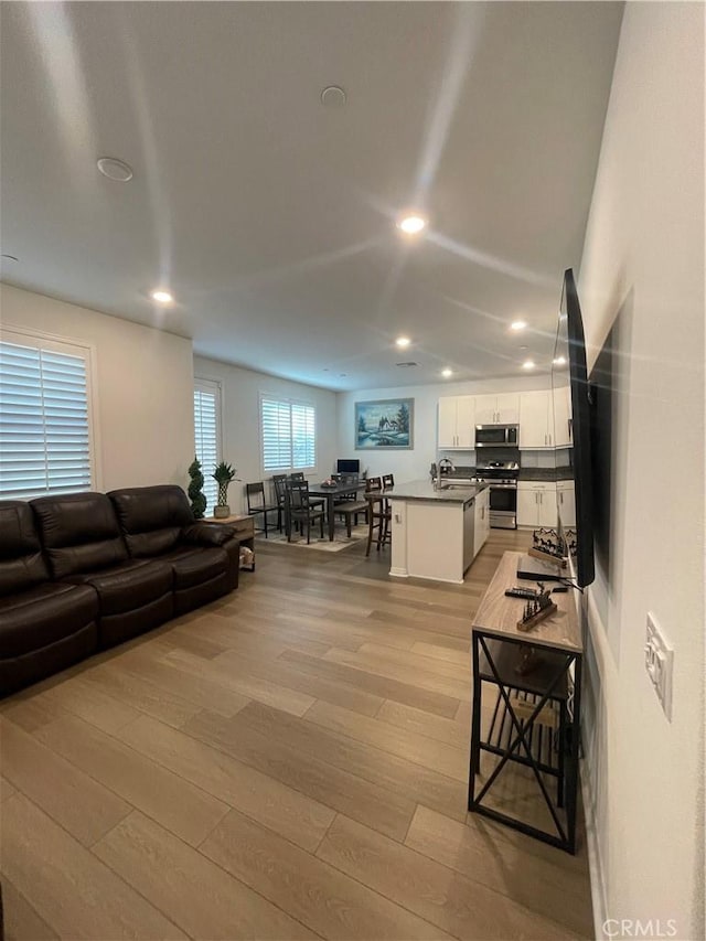 living area with light wood-style flooring and recessed lighting