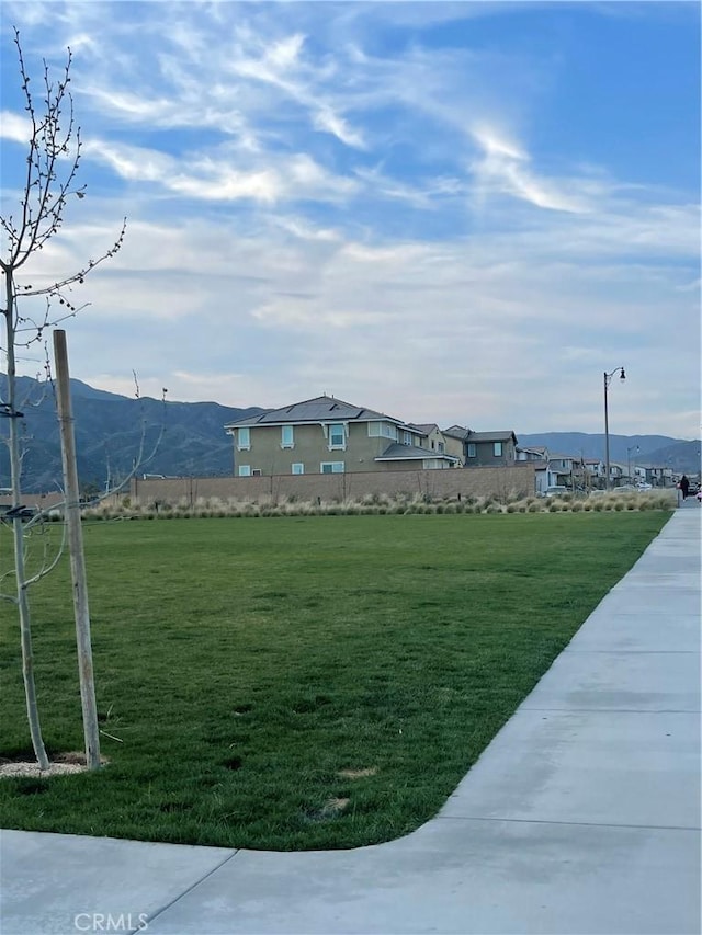 view of property's community with a mountain view and a lawn