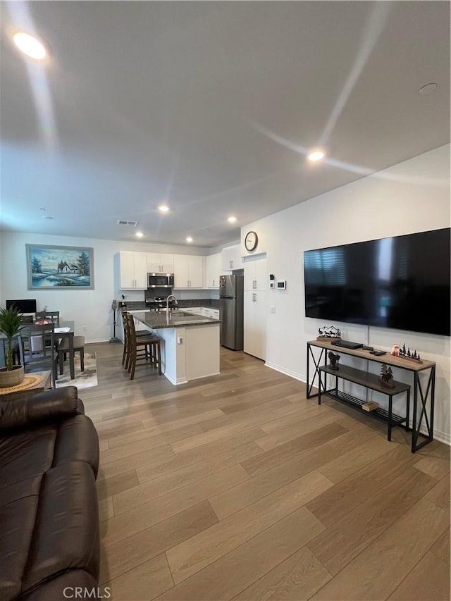 living room featuring light wood-style floors, recessed lighting, and baseboards