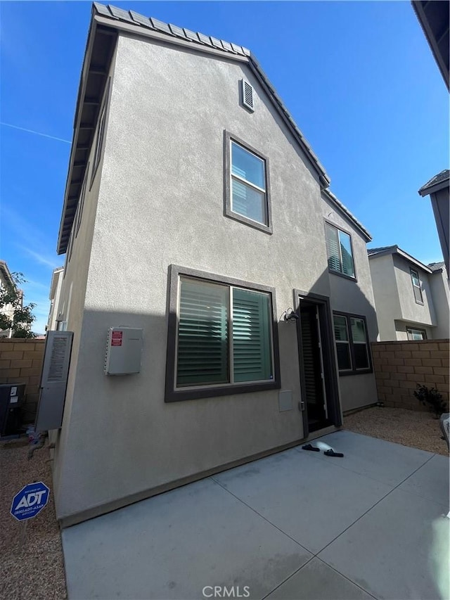 rear view of house with a patio area, fence, and stucco siding