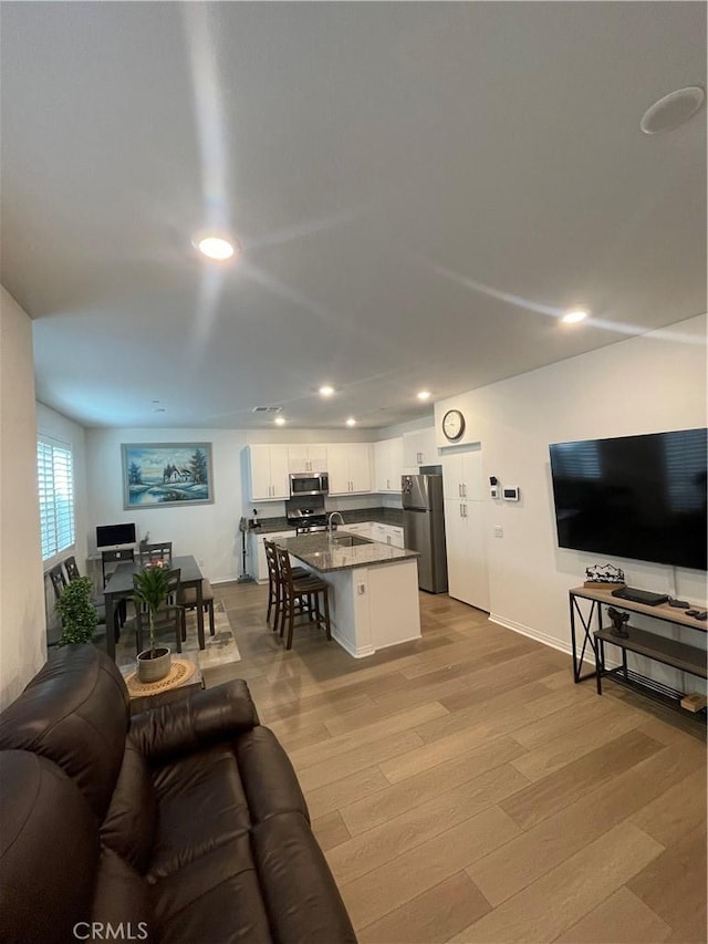 living area with recessed lighting, light wood-type flooring, and baseboards