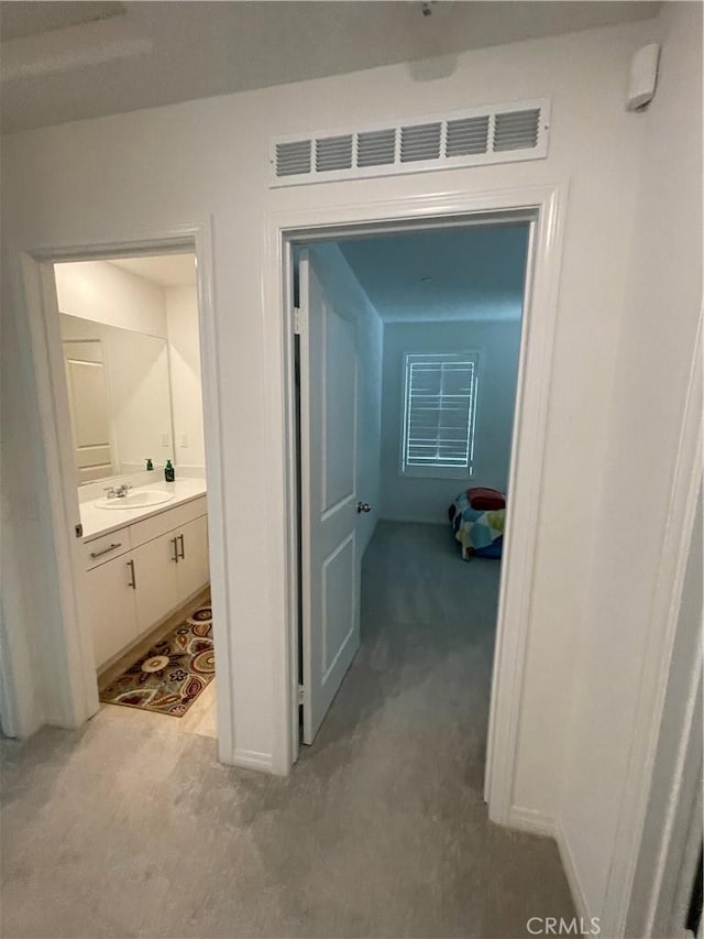 hallway featuring light carpet and a sink